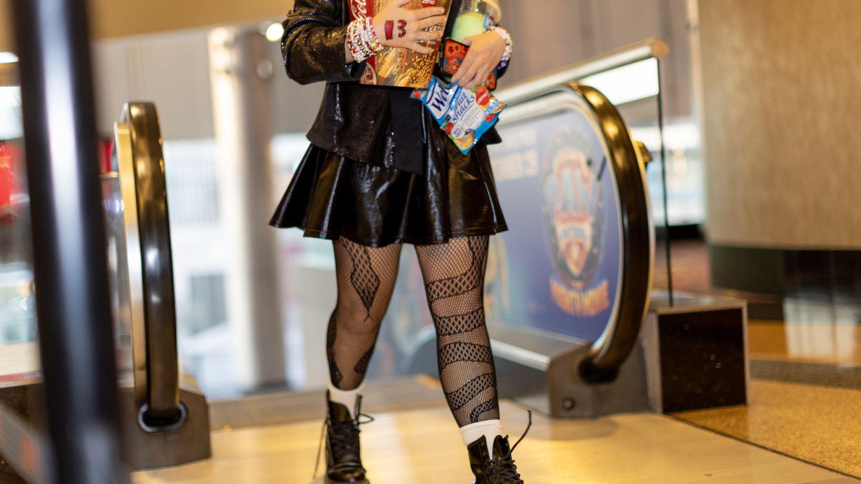A Taylor Swift fan walking into the movie theater dressed in a black "Reputation" inspired outfit.