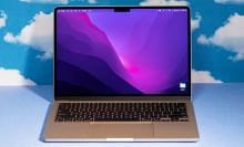 2022 MacBook Air M2 laptop open against a blue backdrop with cloud patterns