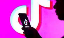  In this photo illustration, a woman's silhouette holds a smartphone with the TikTok logo displayed on the screen and in the background.