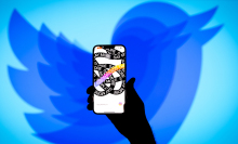 A shrinking Twitter logo behind a smartphone featuring the Threads app.