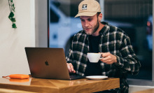 man using a laptop and drinking coffee