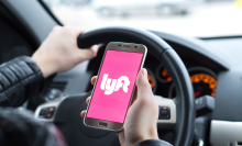 lyft logo on phone with someone driving car