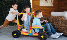 Three kids playing with the Omagles builder set outdoors.