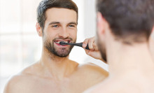Man using Aquasonic black toothbrush in front of mirror.