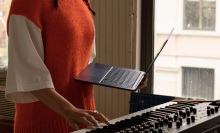person holding m2 macbook air in front of a piano