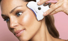 woman pressing facial tool to cheek