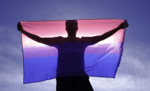 adult man on his back with bisexual flag on a sunny day