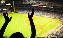 silhouette of fan waving hands in the air at baseball stadium