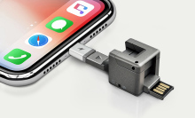 The WonderCube keyring shown connected to an iPhone's charging port