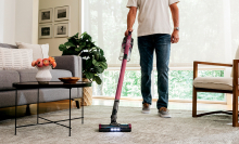 man using shark stick vacuum with lights on living room rug