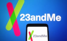 A phone displaying the The 23andMe logo in front of a larger 23andMe logo. 