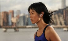 Sweaty person listening to airpod earbuds while looking into the distance with a city skyline in the background