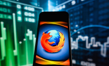 A Mozilla Firefox logo displayed on a smartphone with stock market percentages in the background.