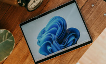 A tablet laying on a wooden surface with a blue and white swirly screensaver on it 