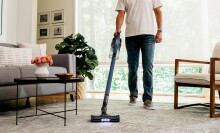 man vacuums living room floor with Shark Stick Vacuum