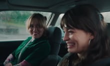 Two women sit in a car laughing.