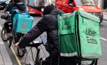 A delivery driver on a cycle with an "Uber Eats" package.