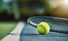 tennis ball and racket laying on court