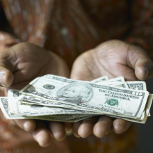 A pair of hands hold out a stack of money.