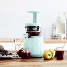 Mint colored juicer making a dark colored beet juice