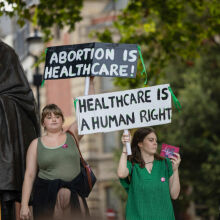 Pro-abortion protesters hold placards which read "abortion is healthcare" and "healthcare is a human right" during a counter-protest on abortion rights at Parliament Square, London.