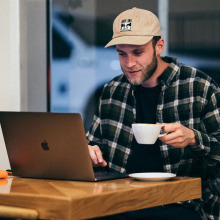 man using a laptop and drinking coffee