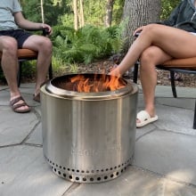 two people sitting around a solo stove bonfire 2.0 on a stone patio