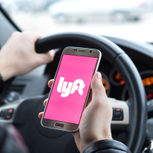 lyft logo on phone with someone driving car