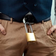 Close-up of a gold padlock hanging from a man's belt.