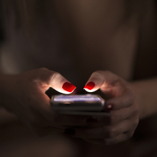 A pair of hands holding a phone in the dark.