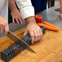 person sharpening knife on cutting board