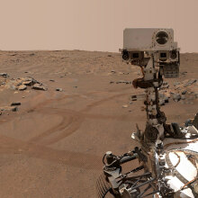 NASA's Perseverance rover, with tracks in the background, exploring the Martian desert.