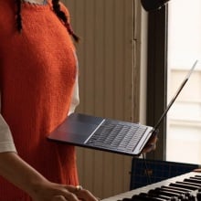 person holding macbook air in front of a piano