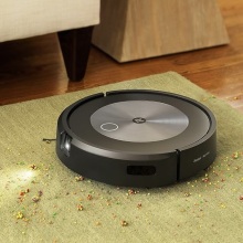 iRobot Roomba j7+ vacuuming up crumbs off a rug