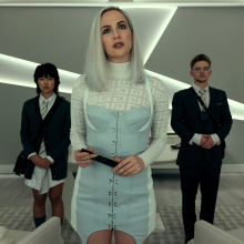 Three well-dressed people in a modern office look directly above the camera looking perplexed.