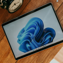 A tablet laying on a wooden surface with a blue and white swirly screensaver on it 