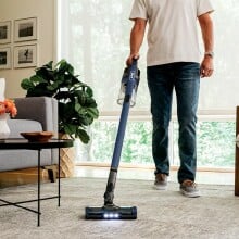 man vacuums living room floor with Shark Stick Vacuum