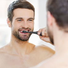 man brushing his teeth in a mirror