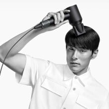 a person uses the dyson supersonic hair dryer in their right hand