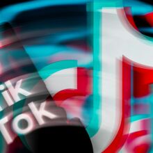 TikTok displayed on a smartphone, blurred, with TikTok icon seen in the background.