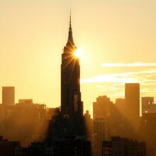 The sun rises behind the skyline of midtown Manhattan and the Empire State Building in New York City.