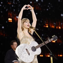 Taylor Swift holding up a hand heart on The Eras Tour.