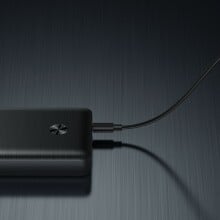 Anker 747 power bank on a black table plugged into its power charger