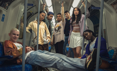 A group of teens stand for a posed photo in a London underground train.