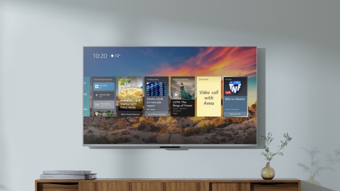 Amazon Fire TV hanging on wall with apps and sunset on screen and TV stand with decor below