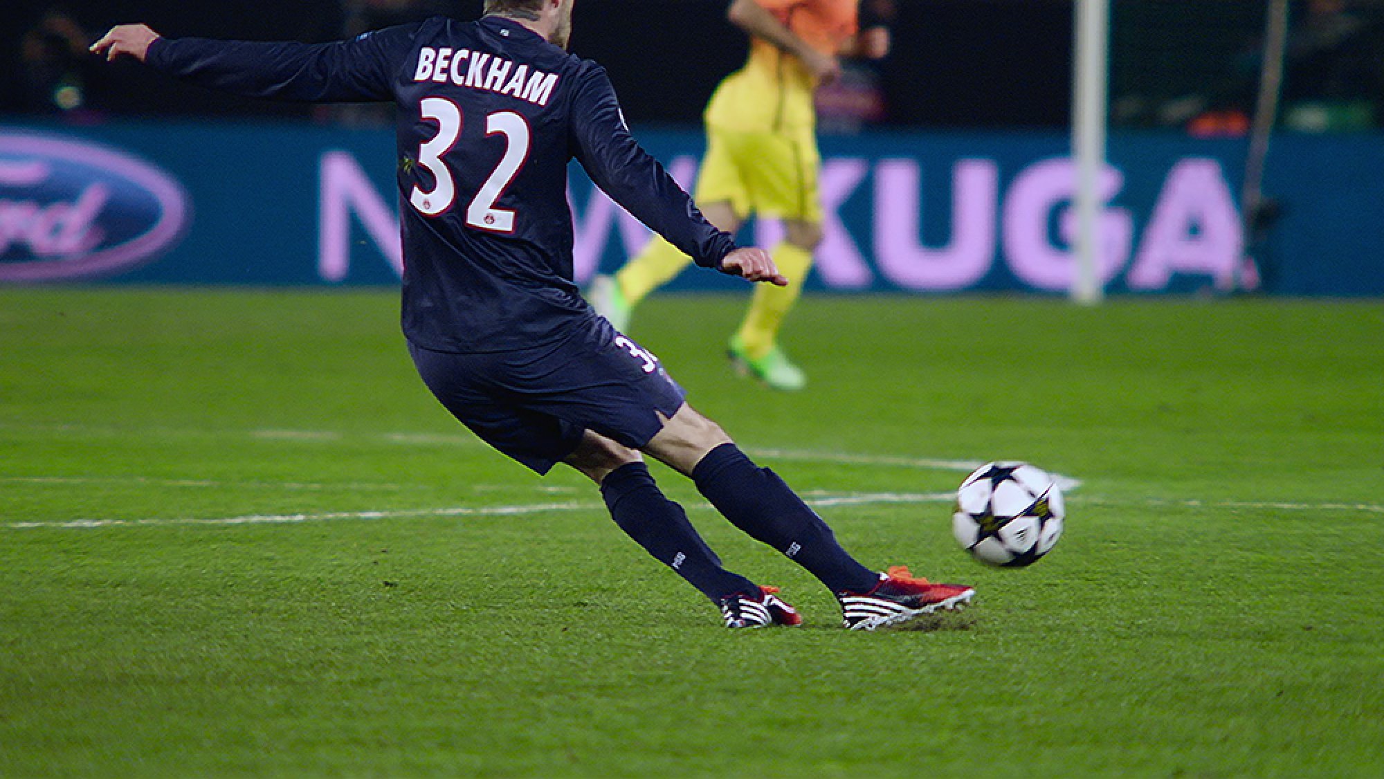 A man in the "Beckham" football shirt kicks a ball.