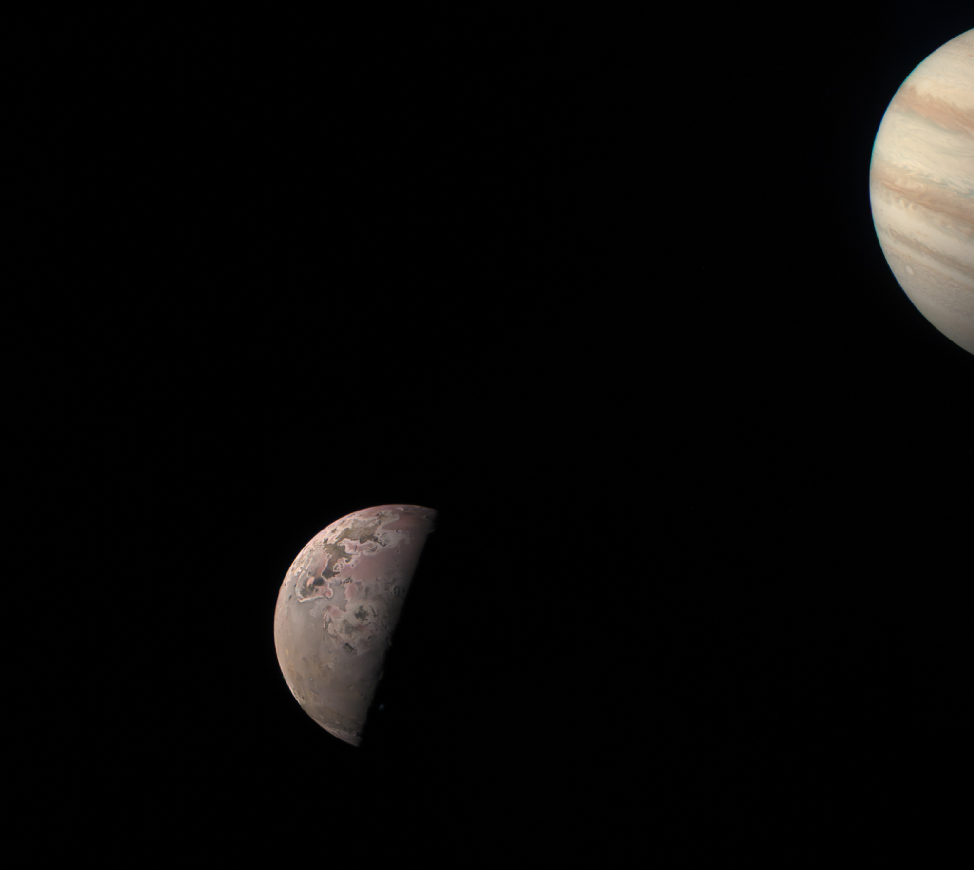 Io, on left, and a partial view of the gas giant Jupiter, on right.