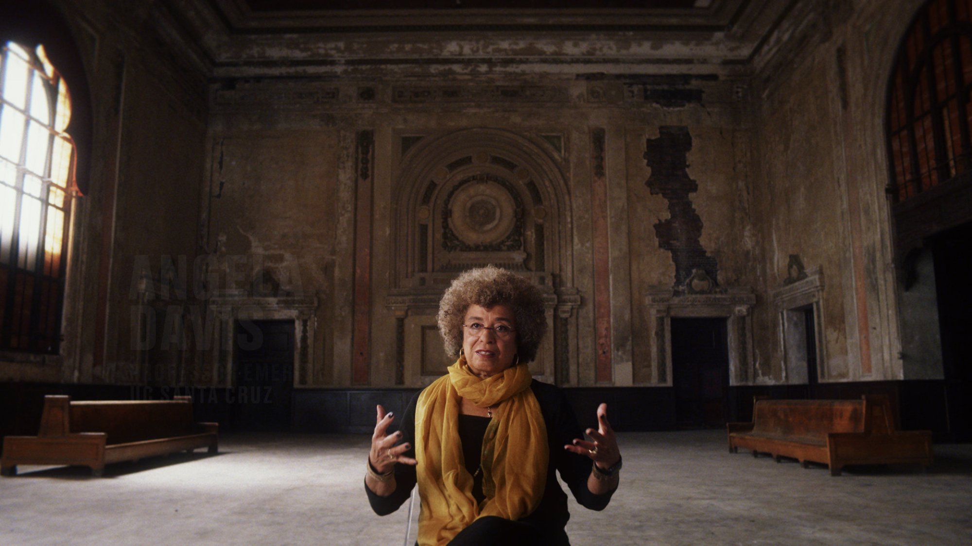 Activist and author Angela Davis sits in the middle of a large stately room in the documentary "13th"