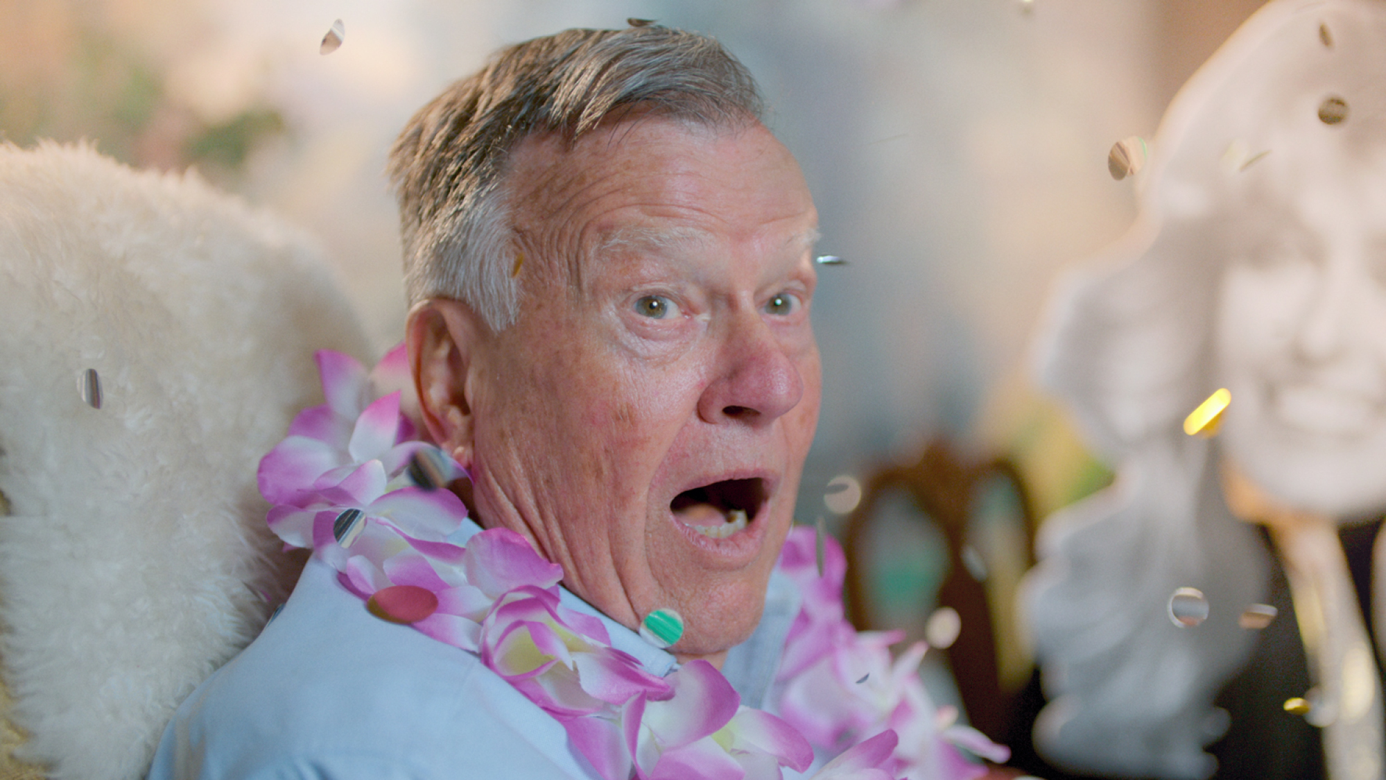 Dick Johnson wearing a flower lei and surrounded with confetti.