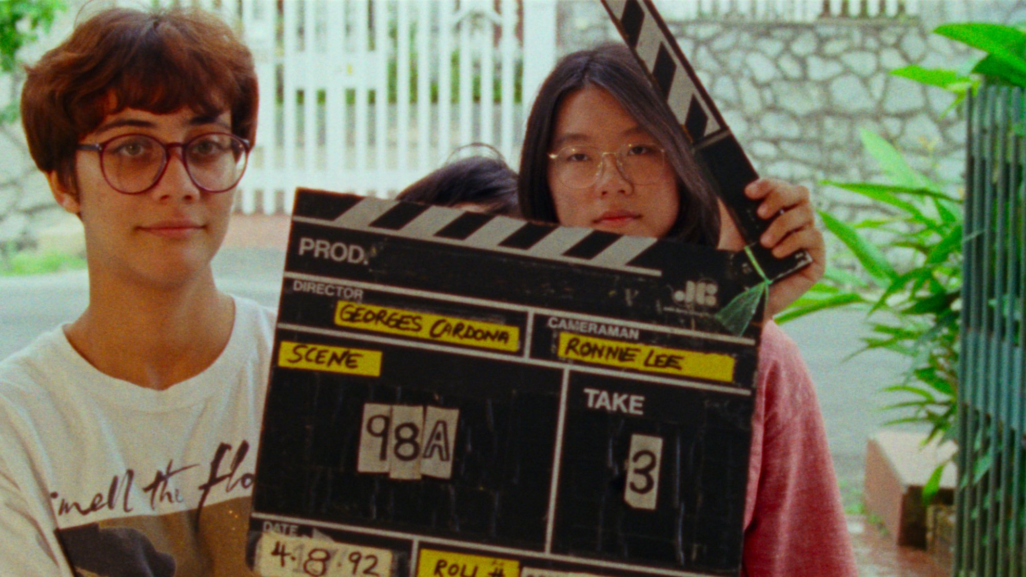 Two young people stand holding a film clapper.